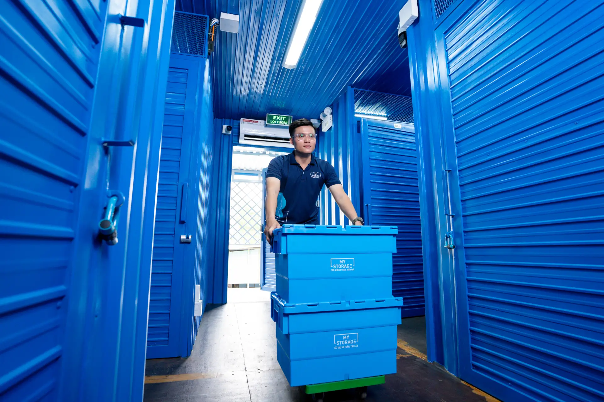 MyStorage施設で青い保管ボックスを運ぶ男性。