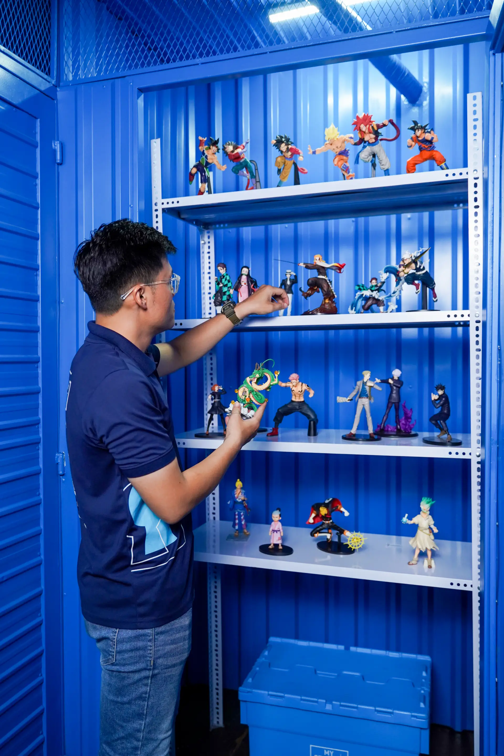 アニメフィギュアを保管ユニットに収める男性