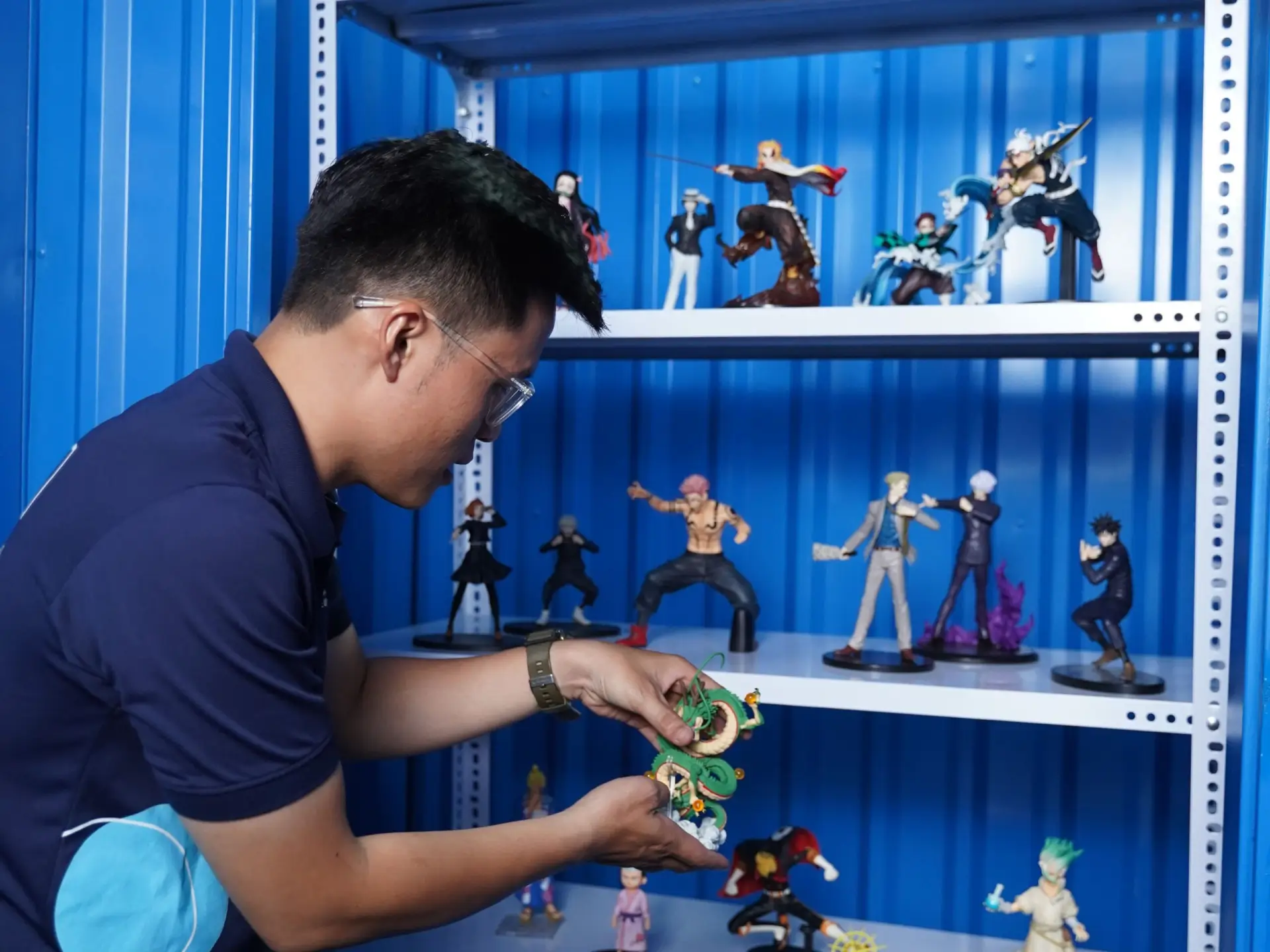空調完備の収納ユニットでコレクションのフィギュアを整理する男性