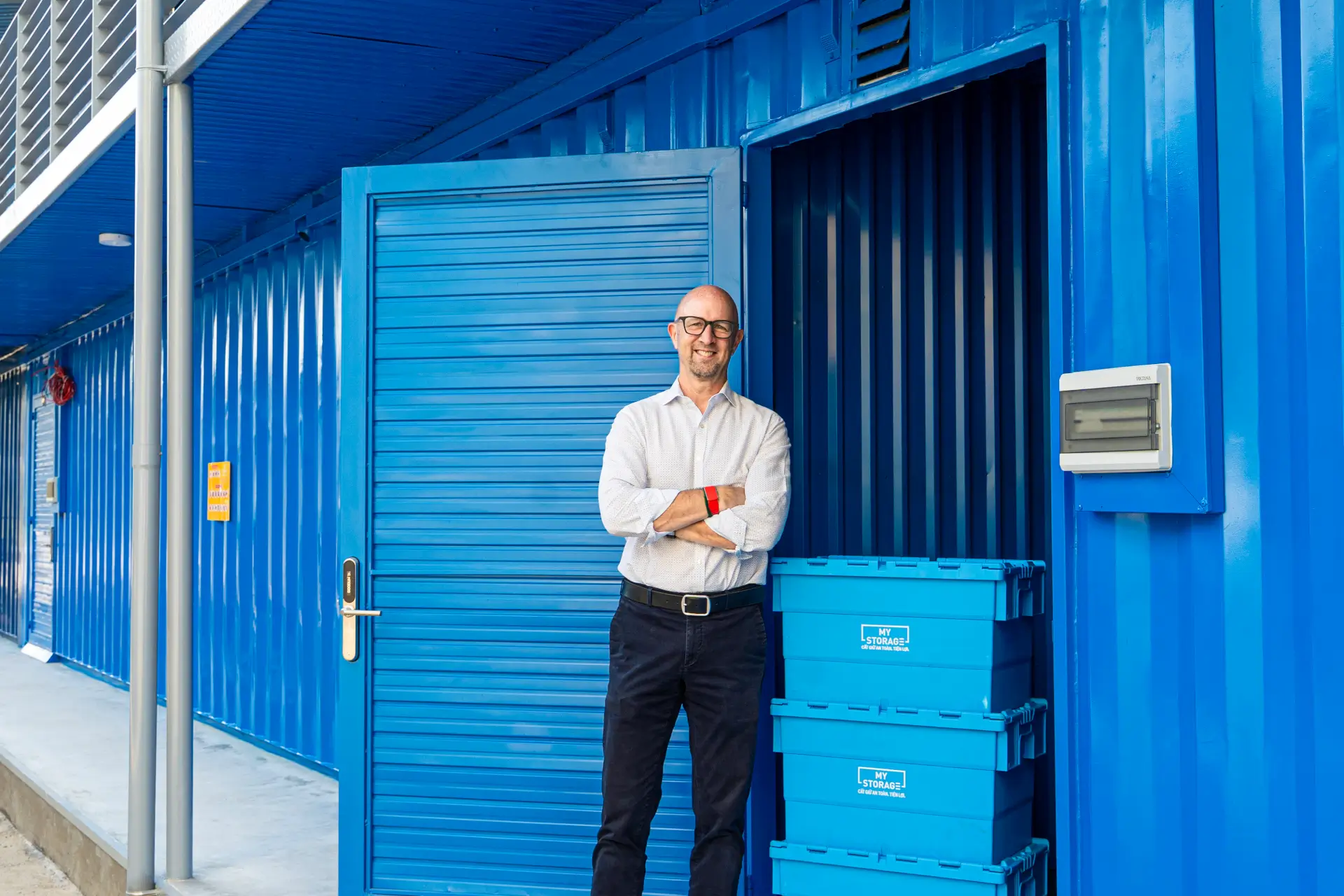 Người đàn ông đứng trước container lưu trữ màu xanh của MyStorage.